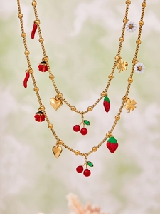 Detail of gold beaded necklace featuring enamel cherry strawberry and clover charms