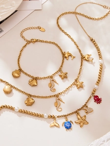 Dettaglio macro di bracciali in acciaio dorato con ciondoli a forma di cavalluccio marino