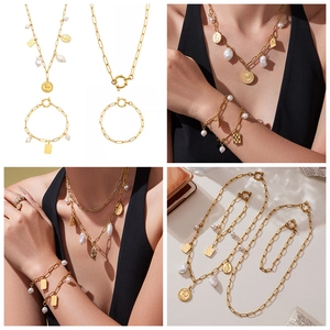 Detail of 18k gold plated paperclip chain set with baroque pearls and embossed pendants