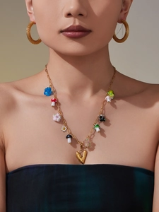 Close-up of a necklace with colorful resin flower and mushroom charms on a female model