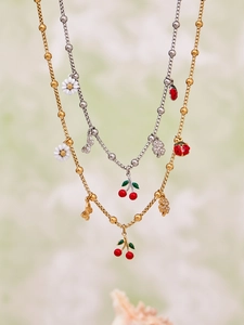 Detailed view of cherry and daisy enamel pendants on dual-tone stainless steel necklaces