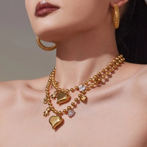 Collier à perles plaqué or 18K avec pendentifs cœur et créoles texturées sur mannequin