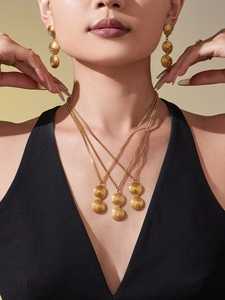 Close-up of layered gold spiral necklaces and earrings set on model's neck