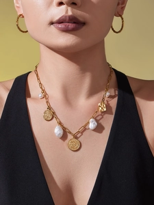Detail of vintage gold coin pendants and irregular pearls on paperclip chain necklace