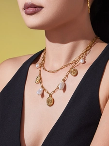 Close-up of double-layer gold necklace with irregular pearl and coin pendants on model