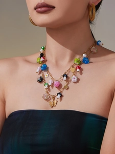Detail of layered gold necklace with mushroom and butterfly resin pendants on model