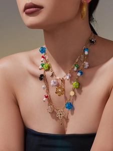 Detail view of gold layered necklace with colorful resin flowers and mushroom charms