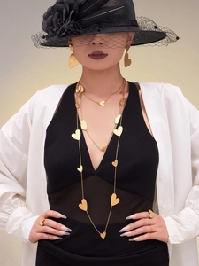Detailed view of layered 18k gold plated heart necklace and earrings on a model