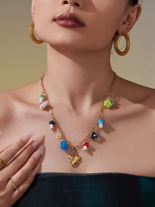 Detailed close-up of gold chain necklace with colorful resin mushroom and daisy pendants