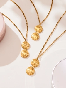 Close-up of three gold double spiral ring pendants on elegant fine chains and off-white background
