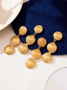 Macro detail of golden drop earrings featuring triple disc spiral textured engraving