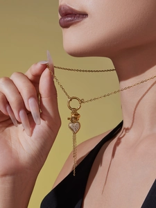 Detailansicht der goldenen Herz-Quastenkette mit Zirkonia-Steinen am Hals eines Models