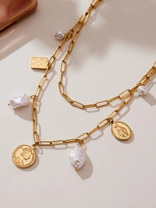 Detailed view of gold chain necklace with vintage coins, pearls and checkered pendant