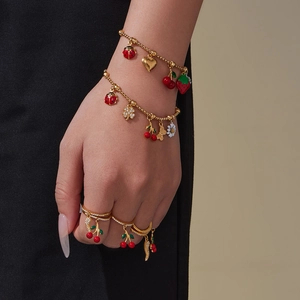 Golden charm jewelry set with colorful enamel fruit and insect pendants on a model