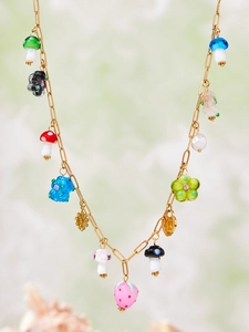 Detail of beaded pendant necklace with colorful forest charms on a gold chain