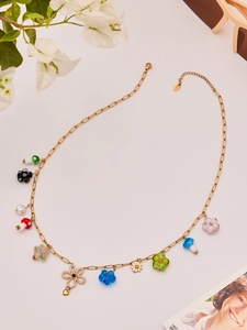 Macro shot of gold necklace with colorful resin mushroom and flower charms plus zircons