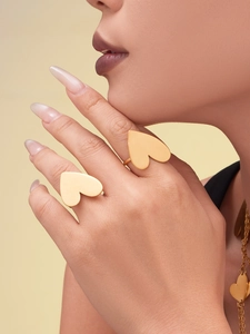 Macro view of matte 18k gold heart-shaped ring and matching pendant necklace on model