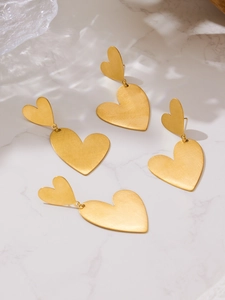 Detail of gold double heart earrings with a brushed texture on a marble surface