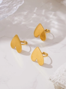Detailed view of three gold brushed heart rings on a white marble surface with soft shadows