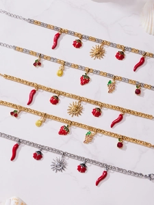 Detail of 18k gold plated beaded bracelets with enamel chili, sun and fruit pendants