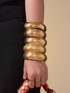 Primo piano di 5 bracciali rigidi placcati in oro 18k con varie finiture testurizzate