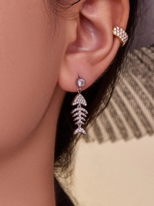 Détail macro de boucle d'oreille arête de poisson et bague d'oreille en zircon doré