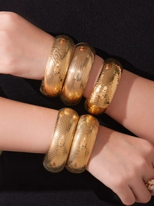 Primo piano di cinque bracciali in acciaio inossidabile placcato oro 18k con texture