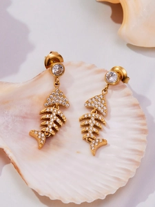 Détails macro de boucles d'oreilles arêtes de poisson dorées avec zircons sur coquillage