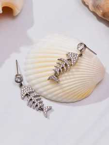 Détail de boucles d'oreilles arête de poisson avec zircons brillants sur un coquillage