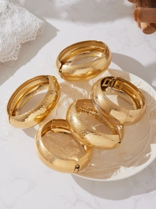 Dettaglio di cinque bracciali in acciaio inossidabile placcato oro 18k con varie texture