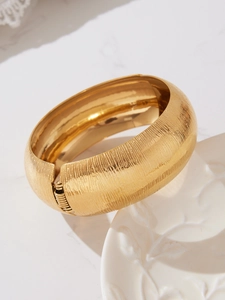 Dettaglio del bracciale in acciaio inossidabile dorato con texture a righe verticali