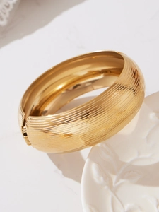 Dettaglio di un bracciale largo in acciaio inossidabile placcato oro 18k spazzolato