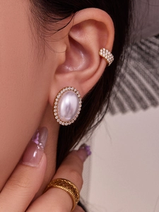 Detalle de pendientes de perla ovalada bañados en oro de 18k con pavé de circonitas