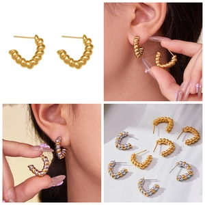 Macro detail of twisted spiral C-shaped hoop earrings in gold and silver plating