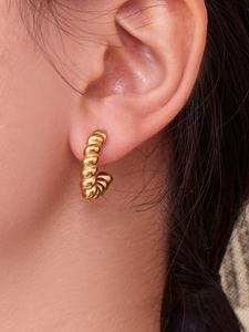 Close-up of model wearing twisted rope hoop earrings with polished 18k gold plating