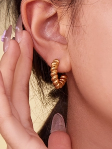 Detailed close-up of 18k gold plated croissant earrings with spiral textured pattern