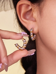 Detail of twisted rope hoop earrings in two-tone gold and silver finish on model