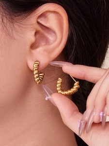 Macro shot of gold twisted rope hoop earrings showcasing chunky vintage texture and C-shape
