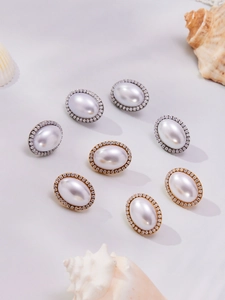 Vista de detalle de pendientes de perlas ovales con halo de circonitas y caracolas