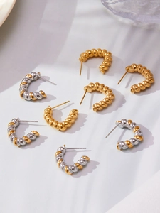 Detailed view of twisted C-shape hoop earrings in gold and silver mixed tones