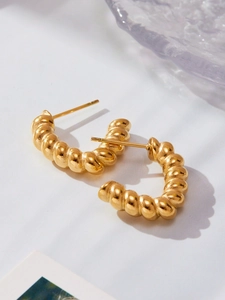 Detail shot of golden twisted croissant earrings with a polished 18k plated metallic finish