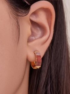 Close-up of model wearing gold ferris wheel earrings with pink and red pavé zircons