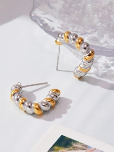 Macro view of twisted bicolor earrings in gold and silver with a polished mirror finish