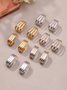 Detailed view of triple-layered C-shape earrings in polished gold and silver finishes
