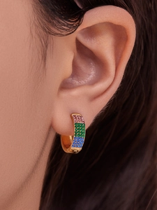 Close-up of gold hoop earring with pink green and blue cubic zirconia worn on ear