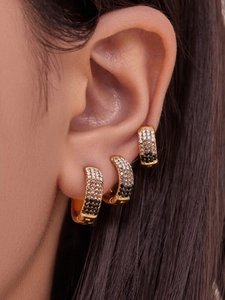 Detailed view of layered gold huggie earrings with black and white pavé cubic zirconia