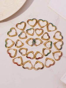 Close-up of heart-shaped earrings with colorful zircon inlay on white marble