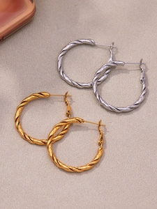 Dettaglio di orecchini a cerchio intrecciati in oro e argento con superficie a spirale