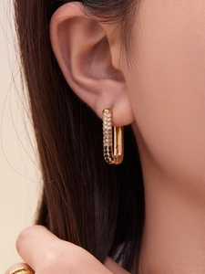 Close-up of gold U-shaped earrings with white and black gradient cubic zirconia