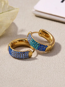 Close-up of gold hoop earrings featuring three rows of gradient blue cubic zirconia
